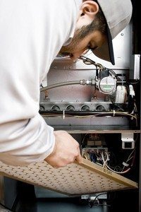 Stock image of HVAC technician replacing filter on furnace